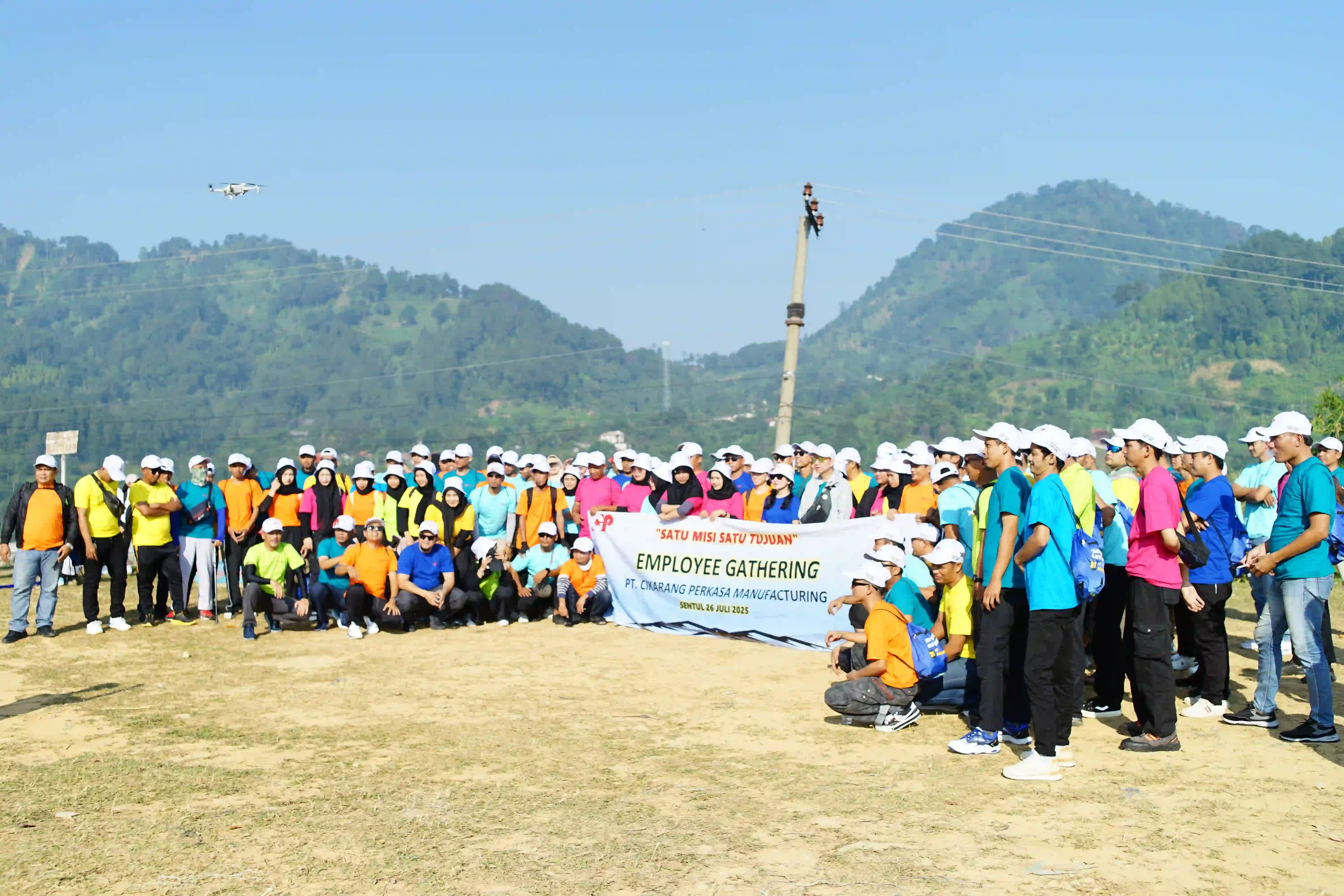 Rombongan karyawan berpose dengan latar belakang pemandangan bukit yang indah.