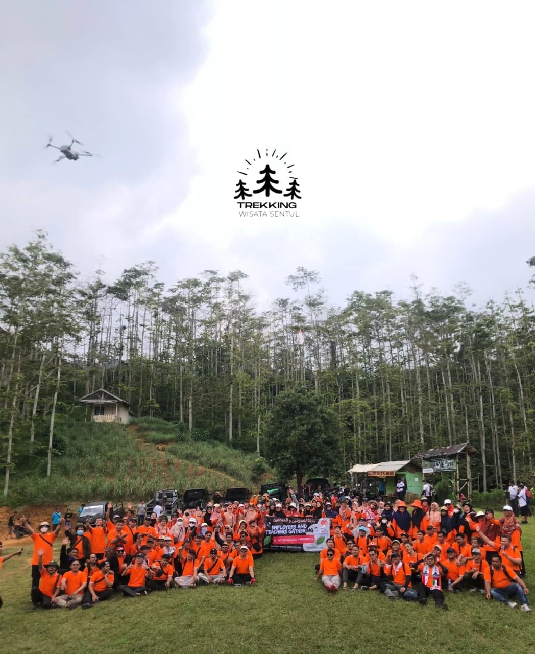 Rombongan besar perusahaan berpose bahagia di area gathering outdoor.