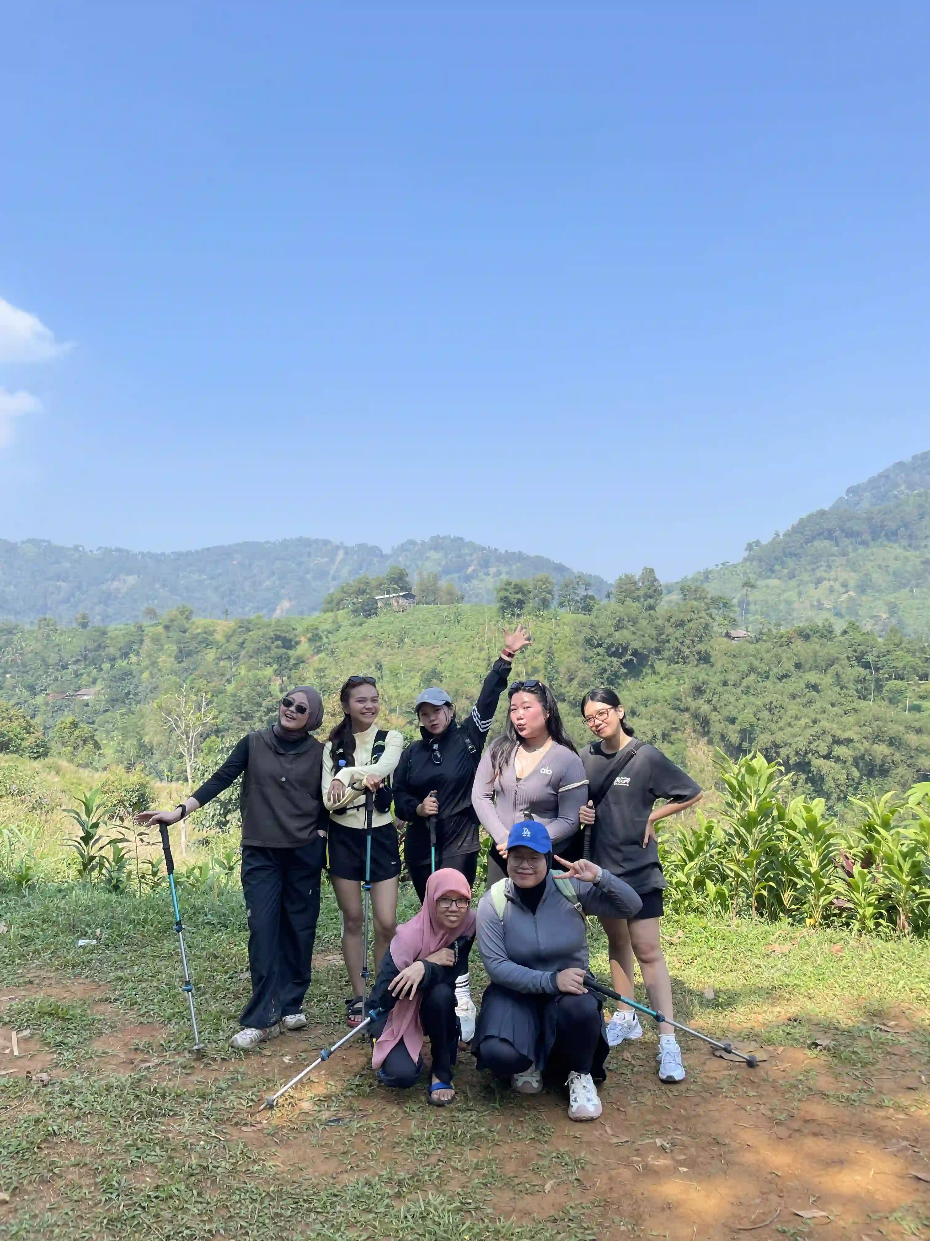Tim perusahaan tersenyum di jalur setapak perbukitan dengan semangat bersama.