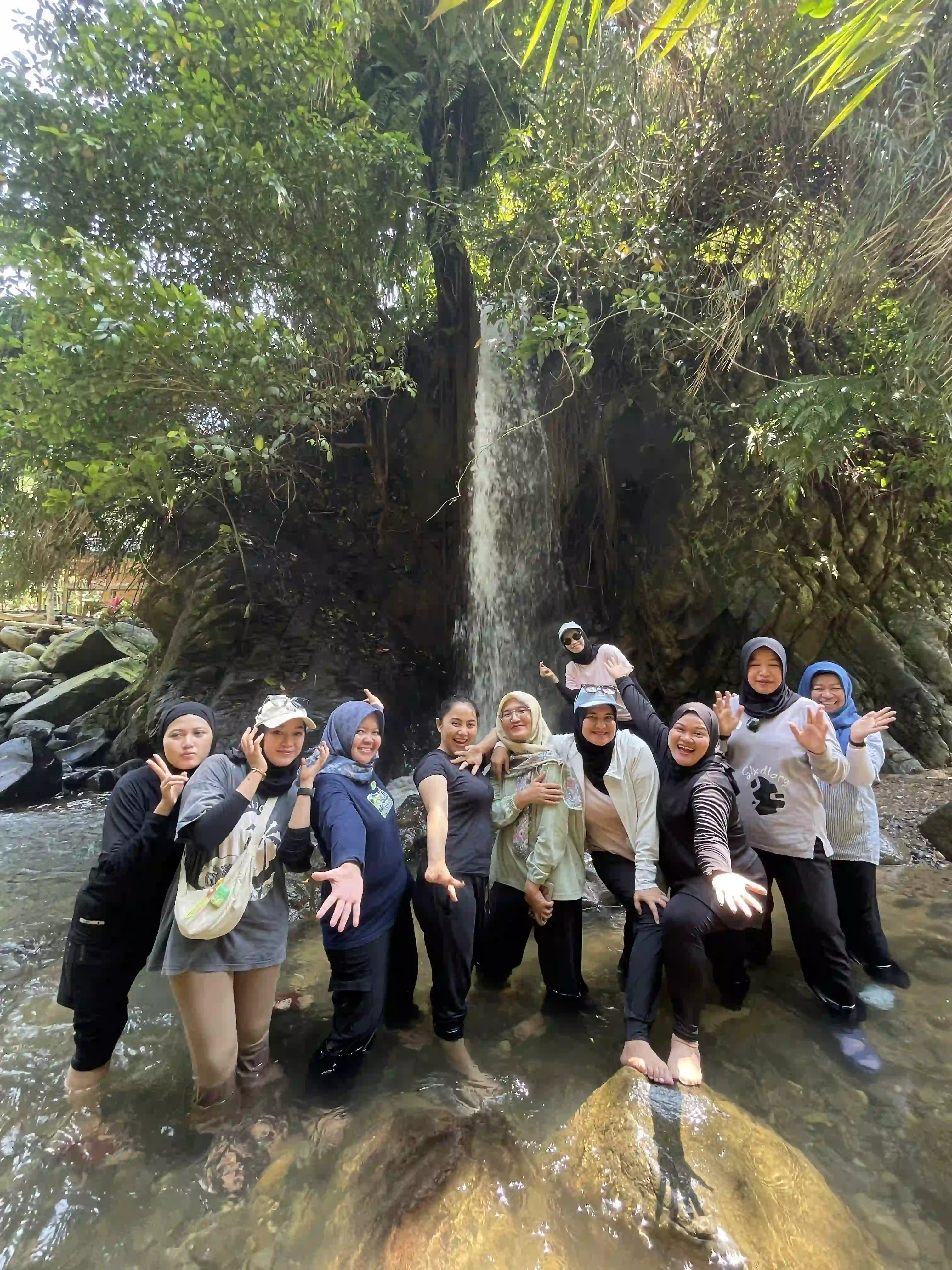 Suasana seru team bonding di area air terjun dengan peserta yang saling mendukung.